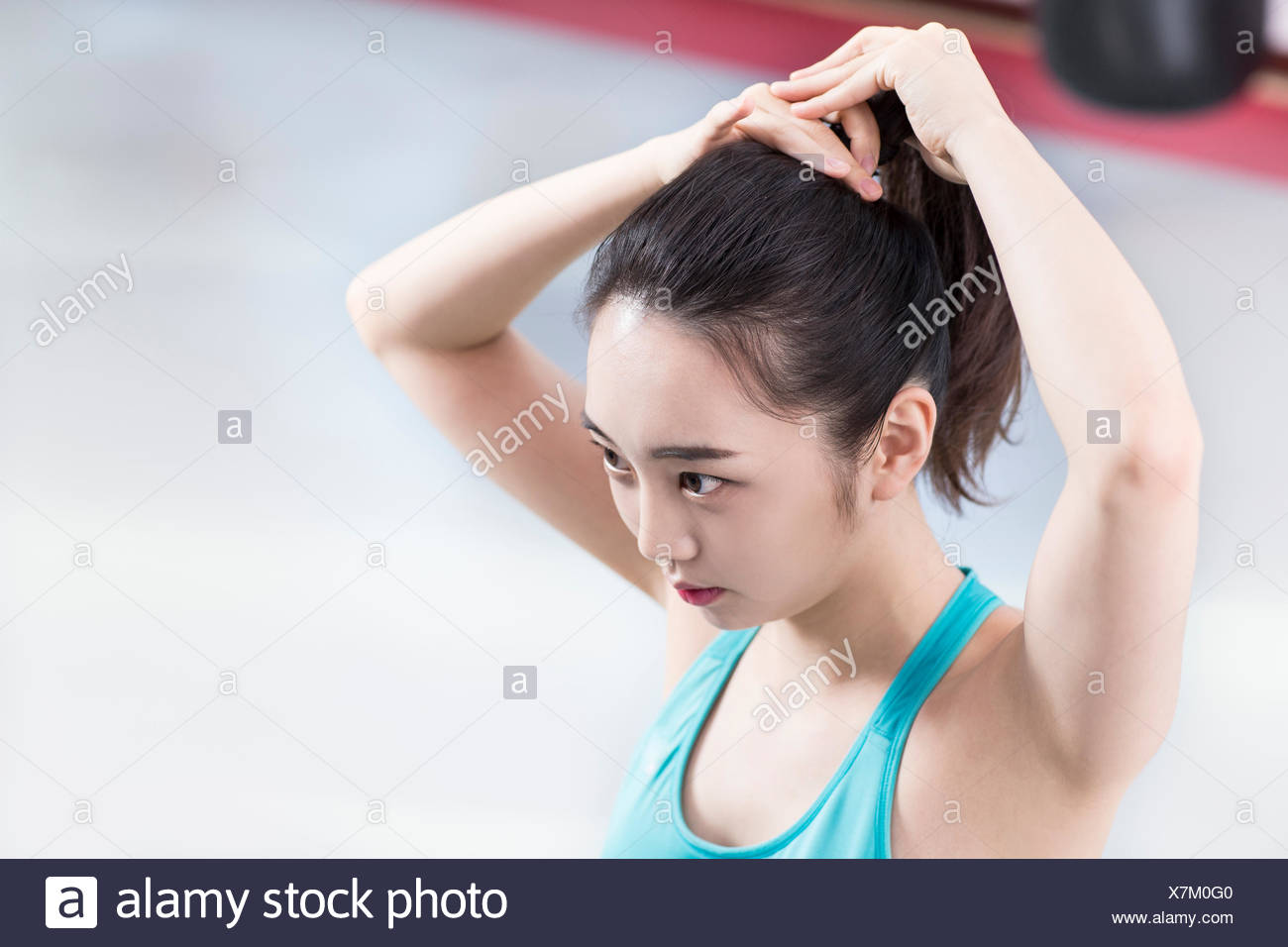 Portrait Of Young Woman In Sportswear Tying Her Hair Back Stock