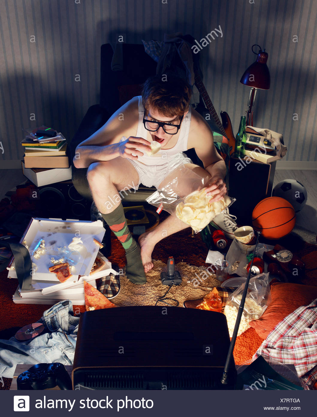 Boy Watching Tv And Eating Chips On Chair Stock Photo
