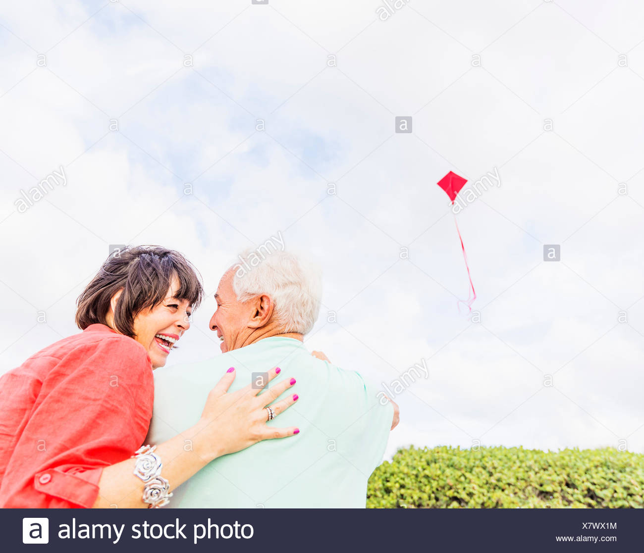 Low-angle view of couple flying kite together Stock Photo
