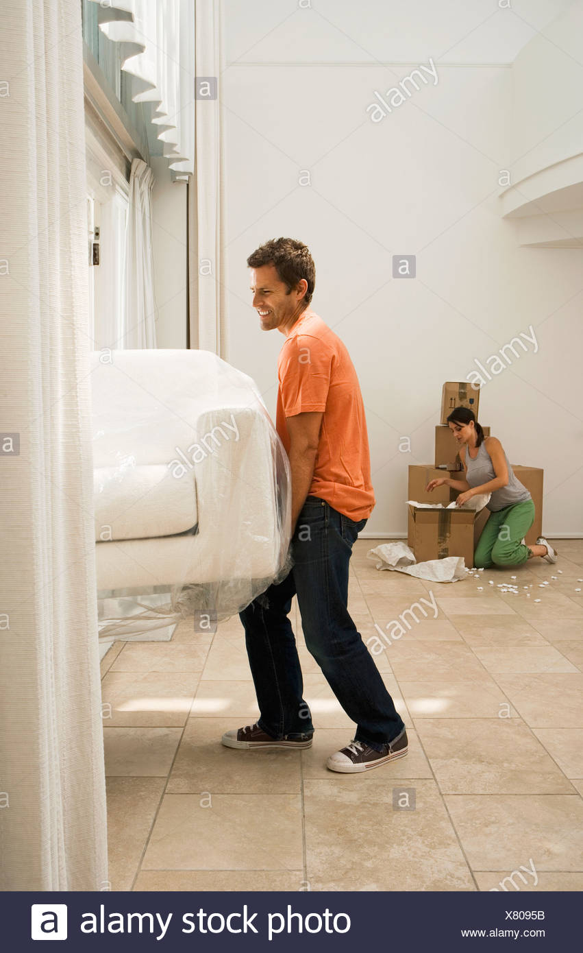 Couple Moving House Man Lifting White Sofa Through Doorway Woman
