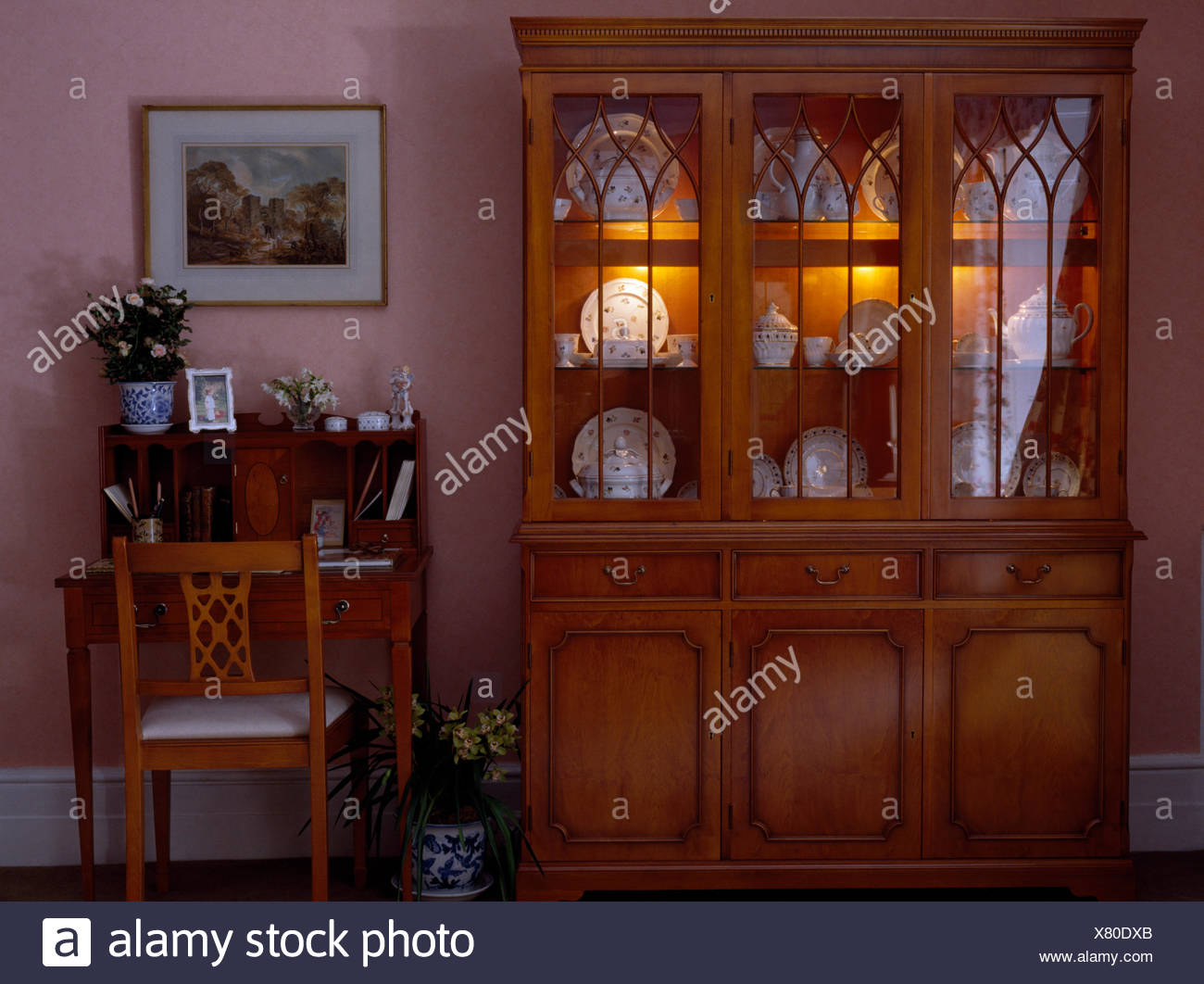 Desk And Chair Beside Glass Front Dresser With Interior Lighting