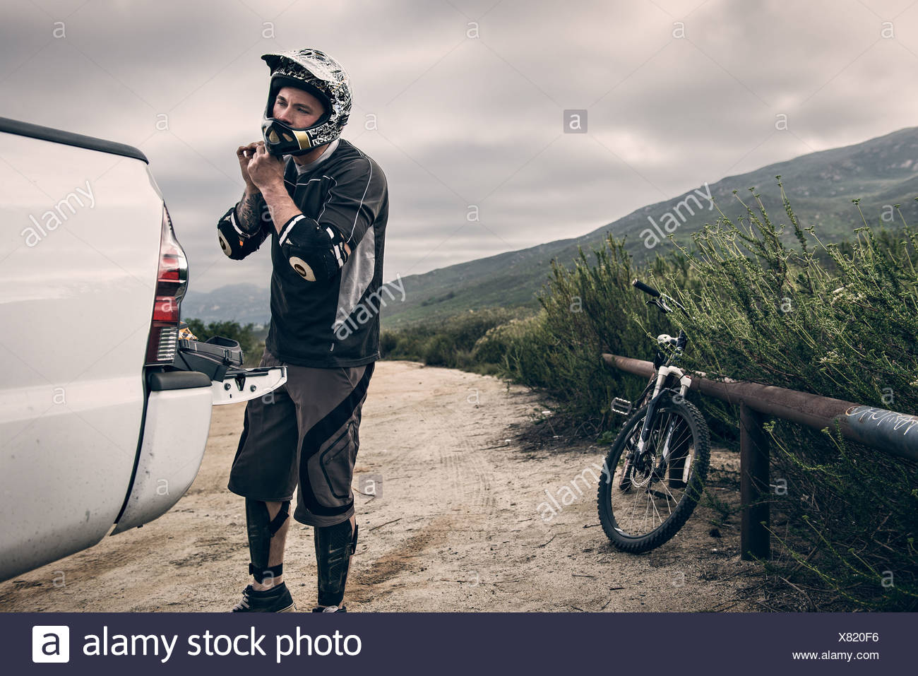 Downhill mountain biker putting on helmet Stock Photo