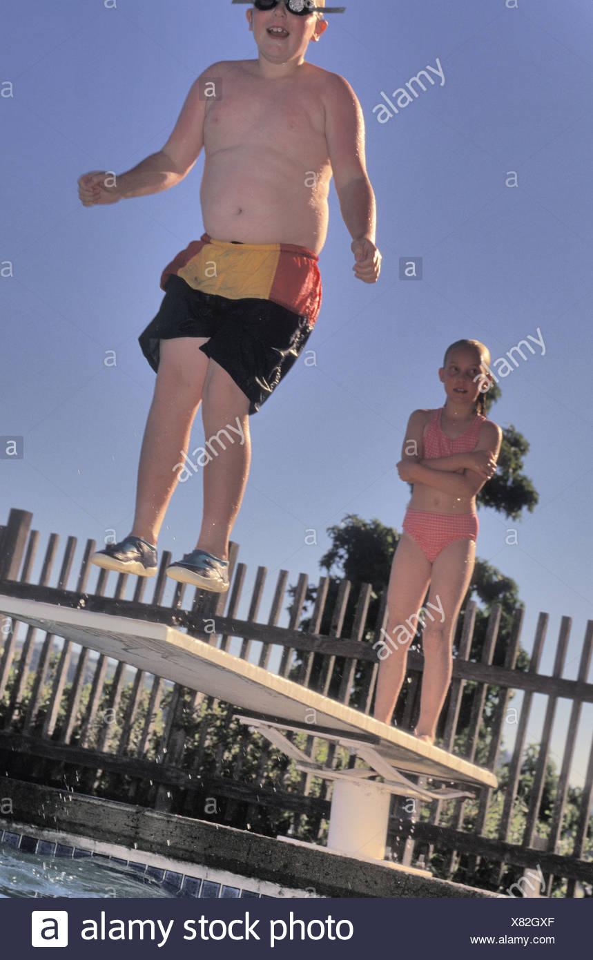 Boy 8 9 Jumping Off Diving Board At Swimming Pool Stock Photo Alamy