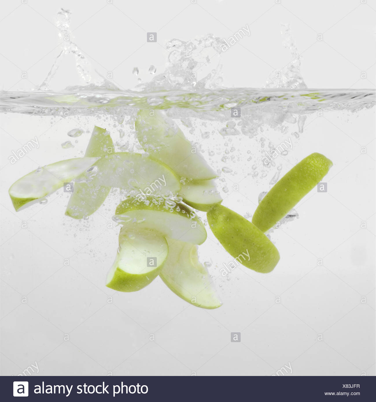 Green Apple Slices Splashing Into Water Stock Photo Alamy