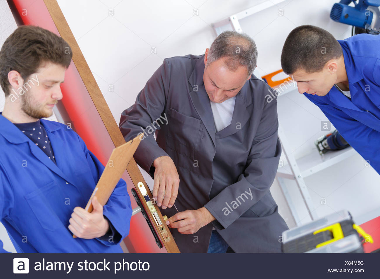 Carpenter Showing Apprentices How To Fix A Broken Door Lock Stock