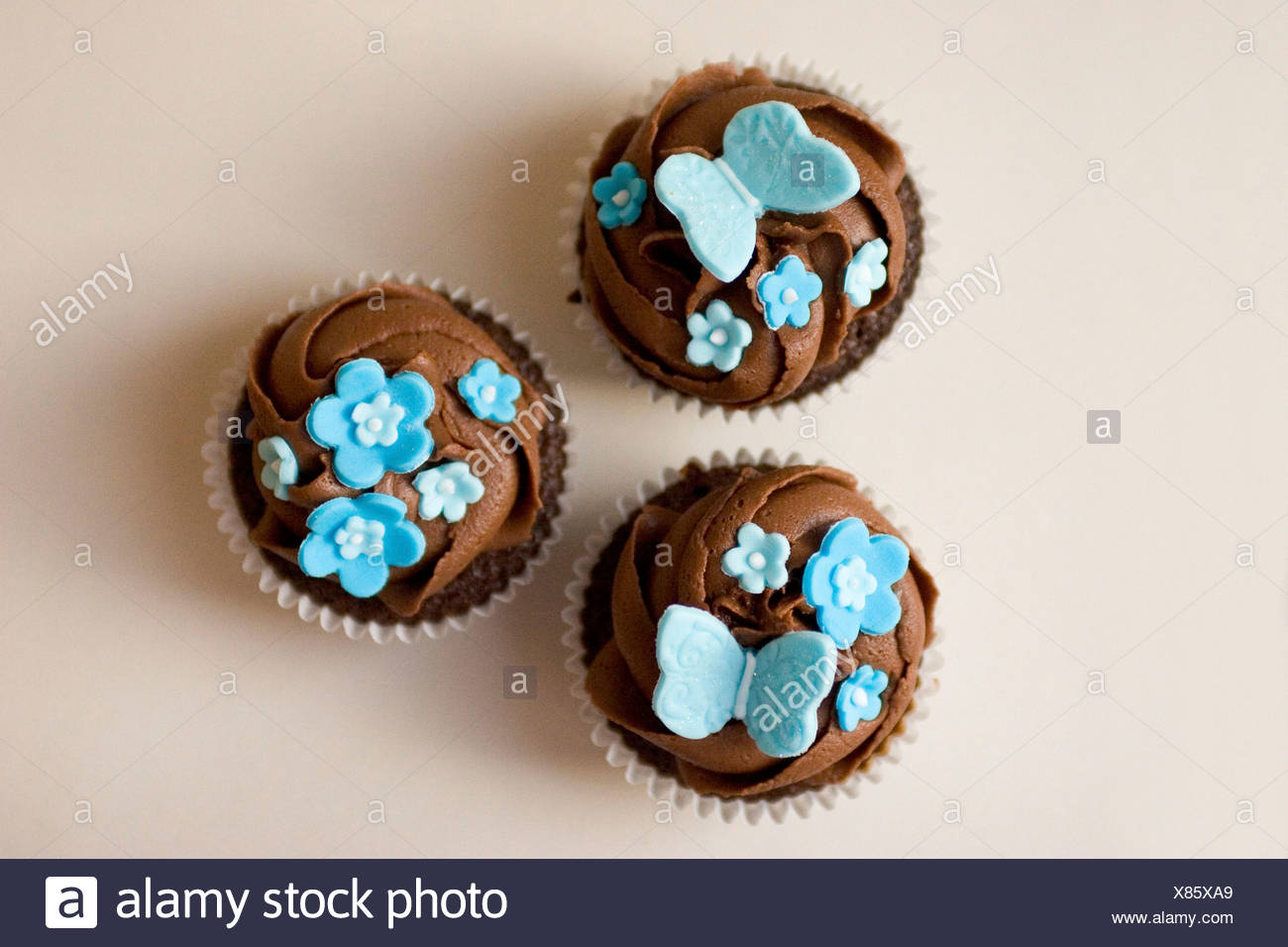 Three Cupcakes With Chocolate Frosting Swirl And Blue Butterfly