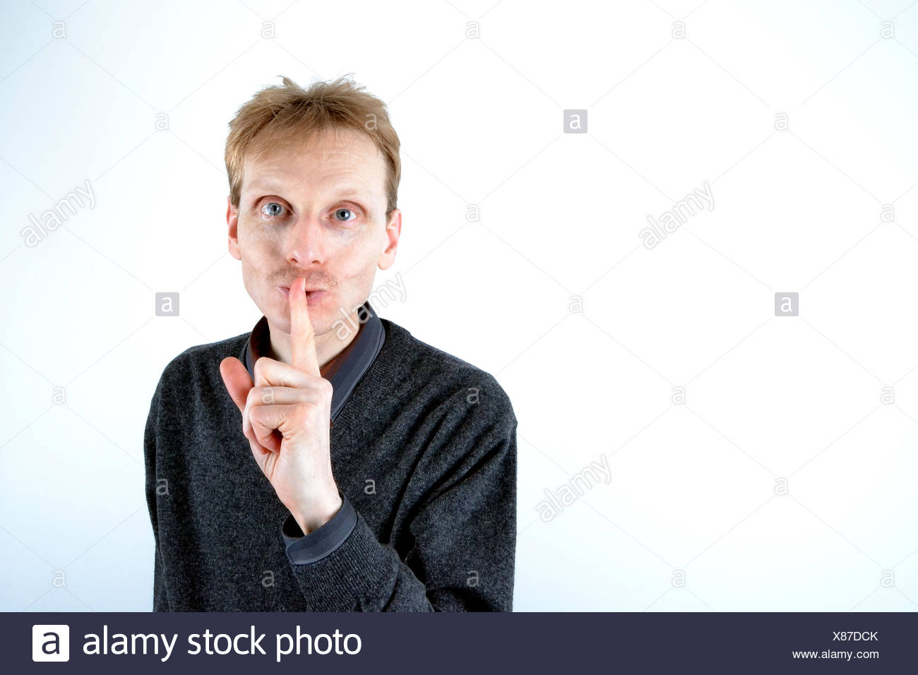 Blonde man who has his finger at the mouth Stock Photo
