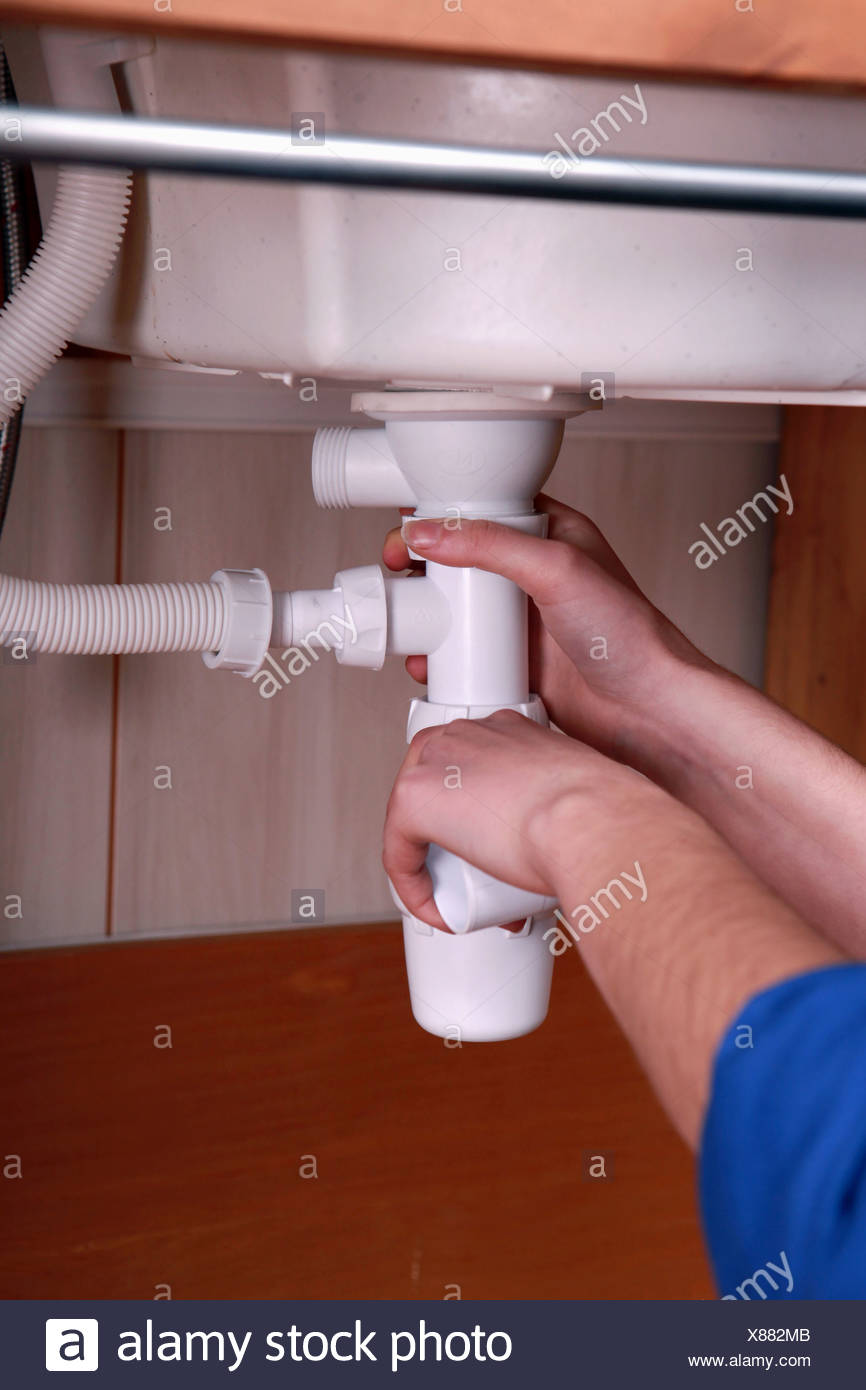 Plumber Fitting The Waste Pipe To A Kitchen Sink Stock Photo