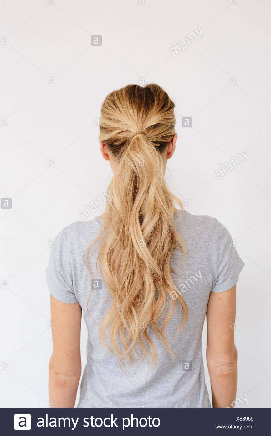 A Young Woman With Long Blond Wavy Hair Tied In A Ponytail Back
