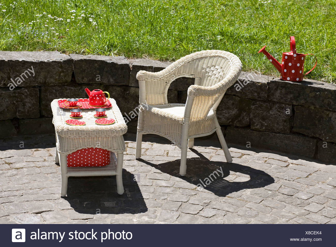 A Wicker Chair And Table With A Child S Tea Set Outdoors Stock