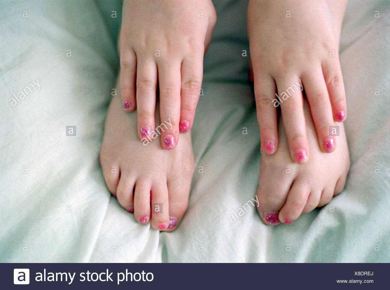 Close up of feet and hands of young girl wearing pink nail polish ...