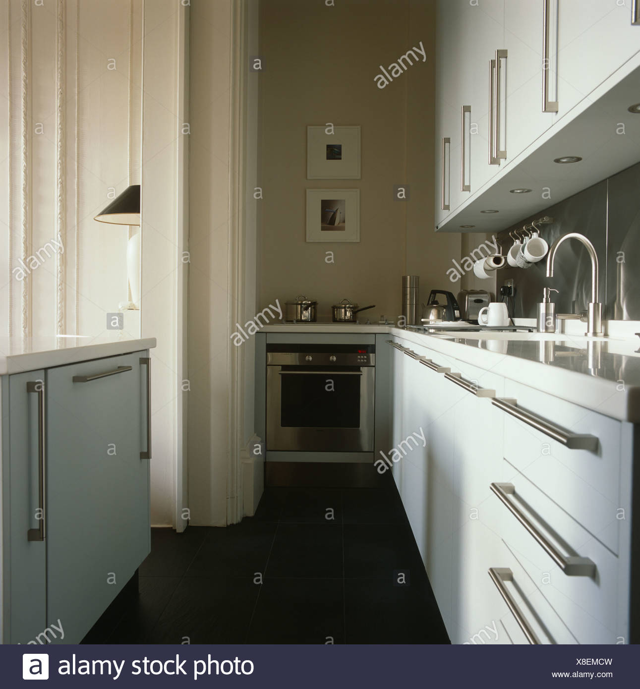Brushed Steel Handles On White Cabinets In Galley Kitchen With