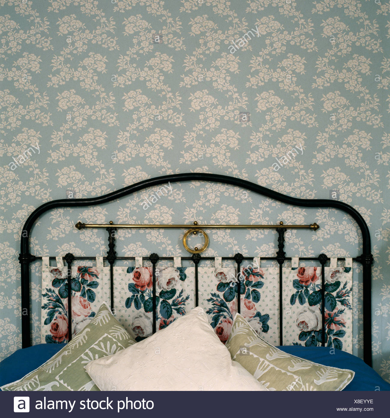 Close Up Of Lloral Hanging On Cast Iron Bed With Cushions In Bedroom With Blue And White Floral Patterned Wallpaper Stock Photo Alamy