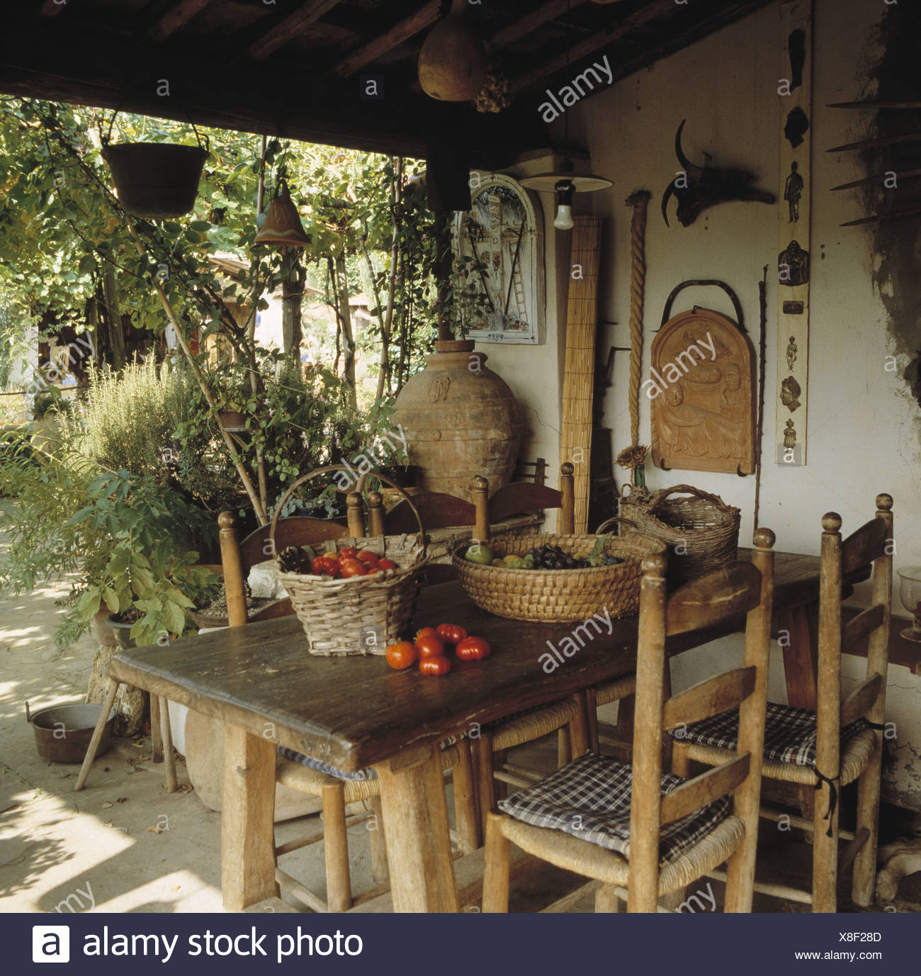 Rustic Wooden Table And Ladder Back Chairs On Veranda Of Small