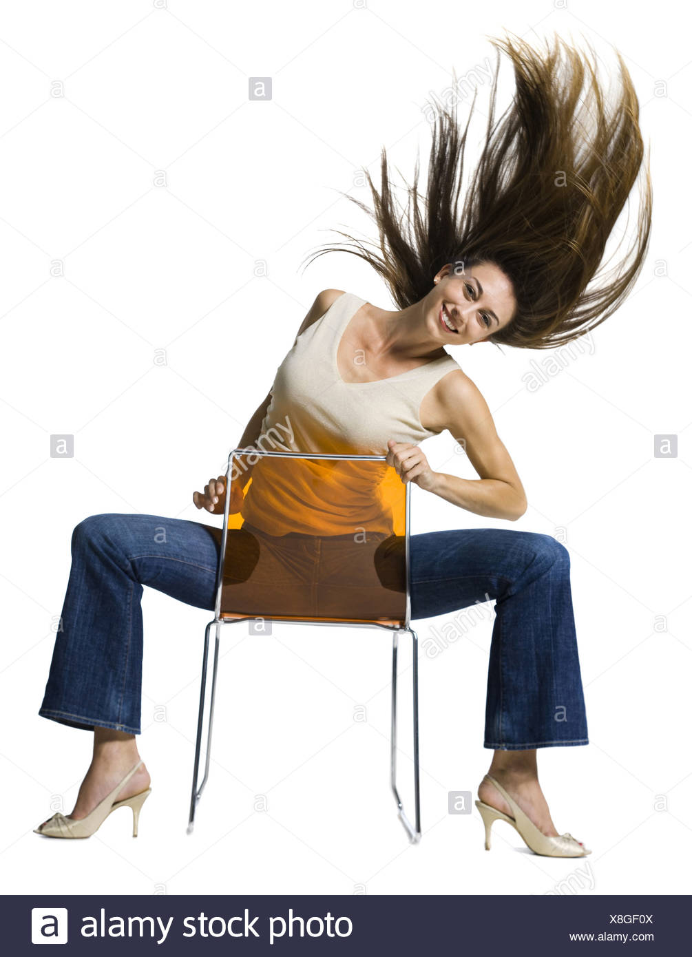 Woman sitting backwards on chair and tossing hair - Stock Image.
