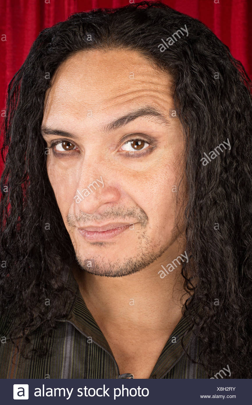 Close Up Of Skeptical Latino Man With Long Hair Stock Photo