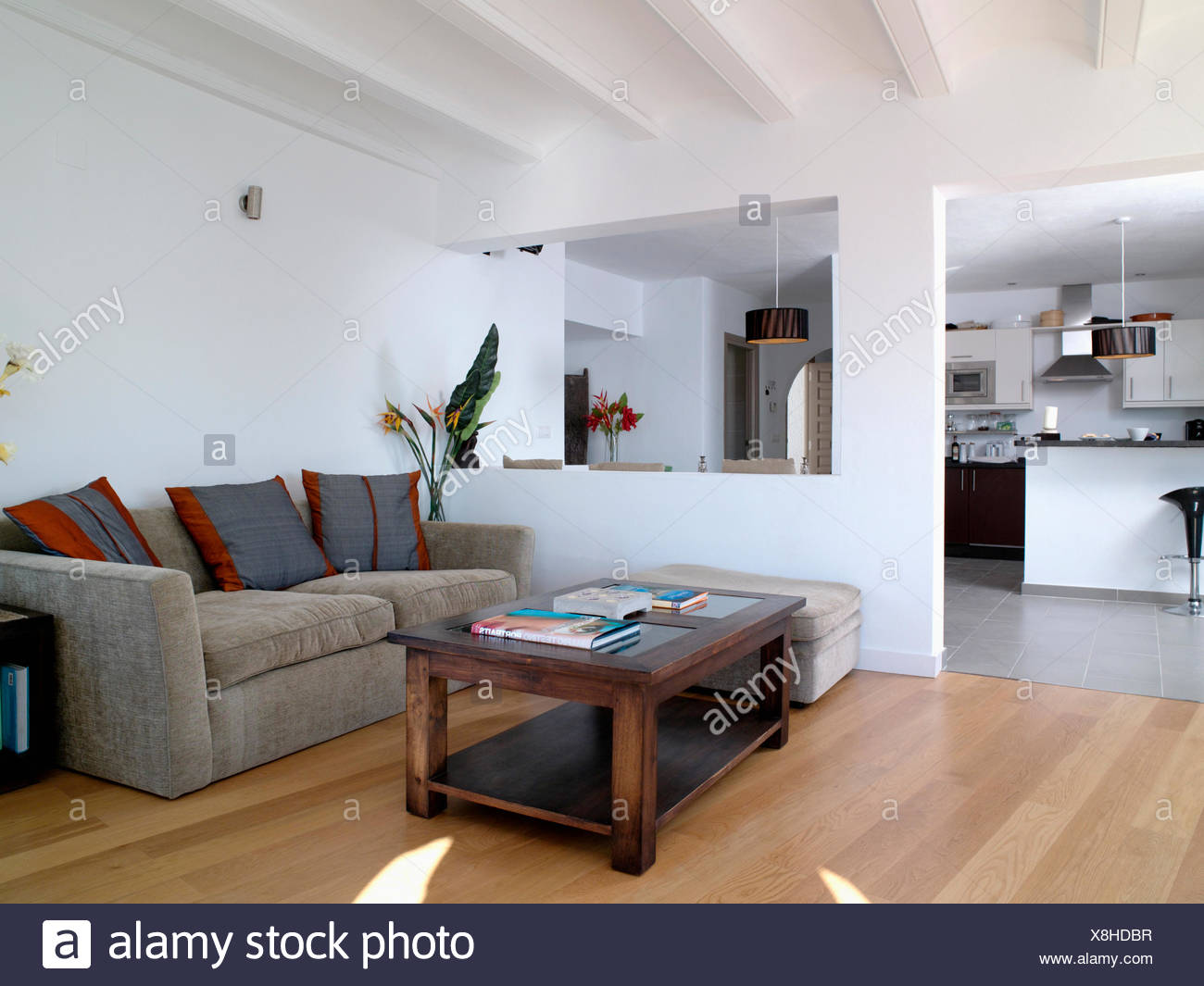 Dark Wood Coffee Table And Gray Velour Sofa In Modern White Open Plan Coastal Living Room With Double Doorway To Kitchen Stock Photo Alamy