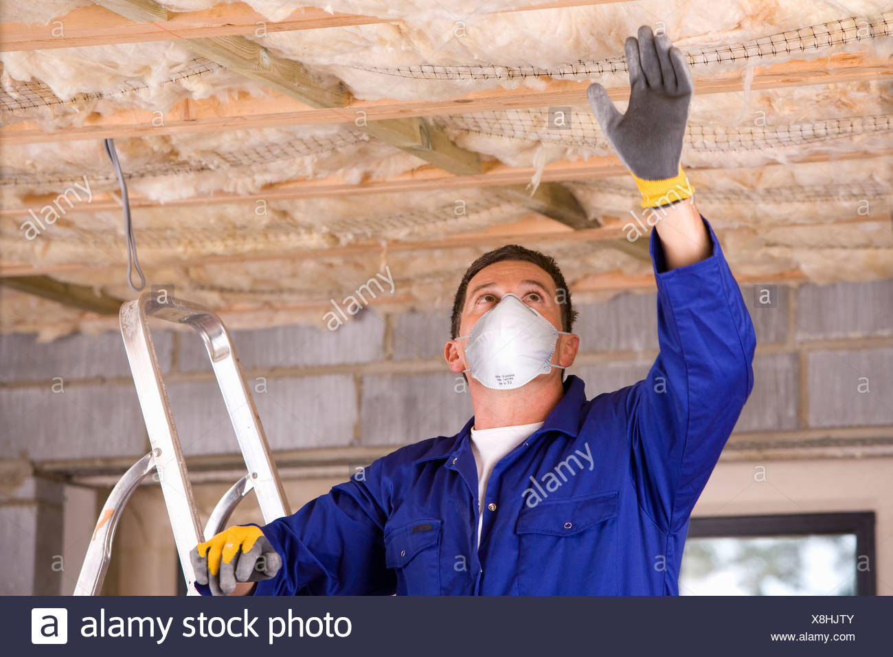 Man Wearing Protective Mask And Installing Ceiling