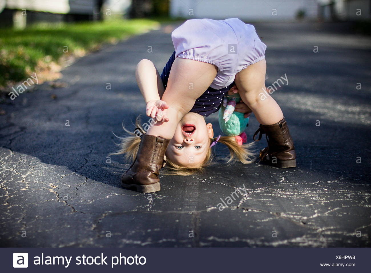 Girl bending over and looking through her legs upside down Stock Photo
