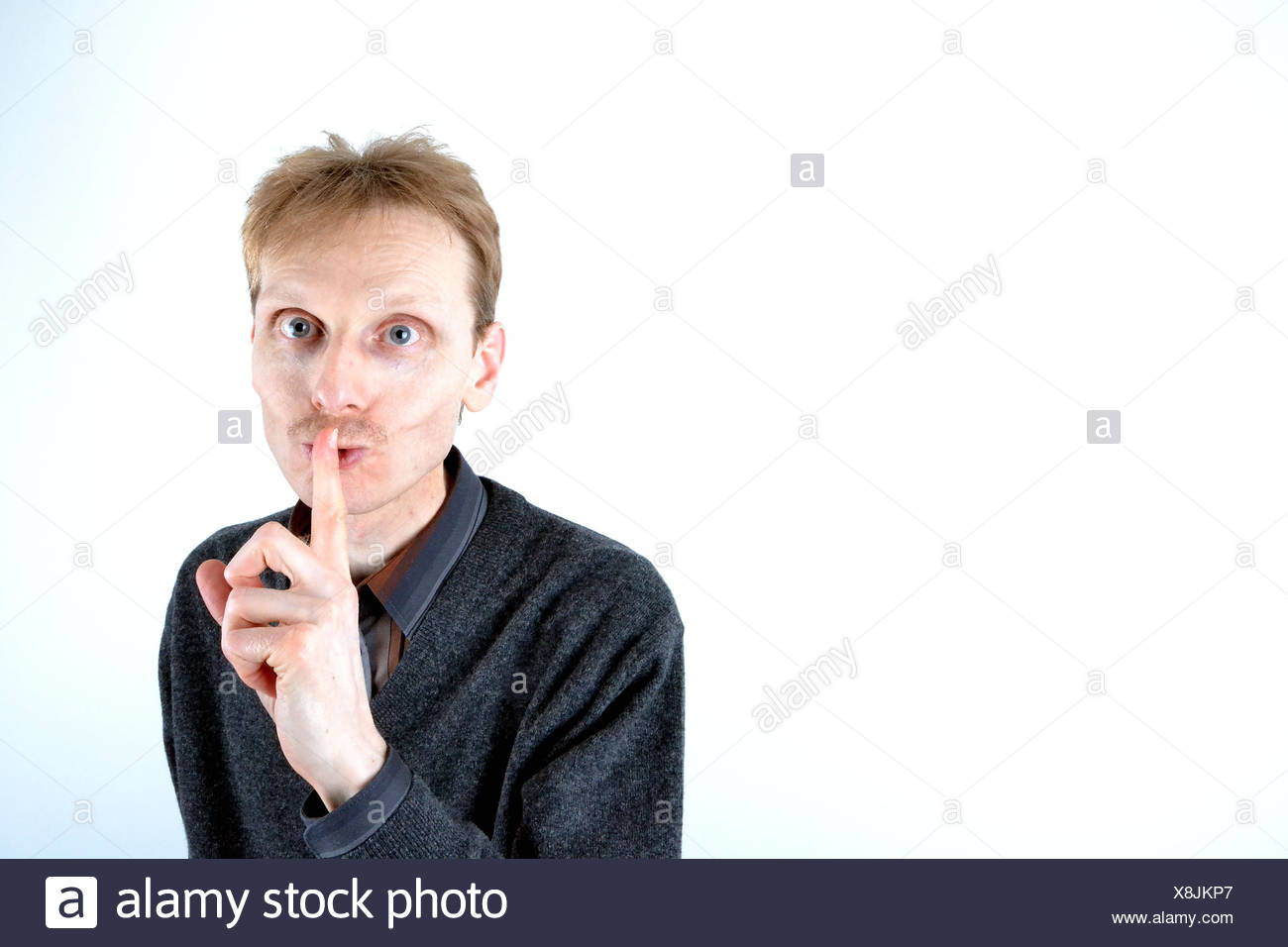 Blonde man who has his finger at the mouth Stock Photo