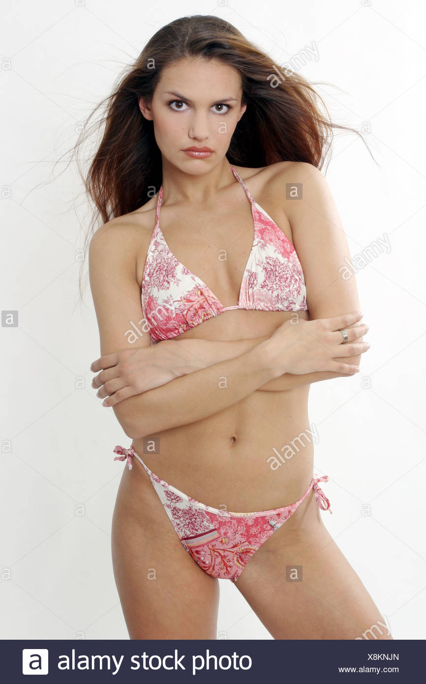 brunette, longhaired woman wearing bikini, crossing her arms, looking at camera. Stock Photo