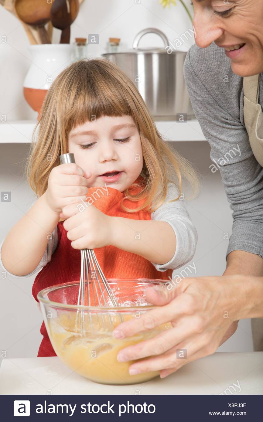 three years old child whipping cream in glass bowl with metal ...