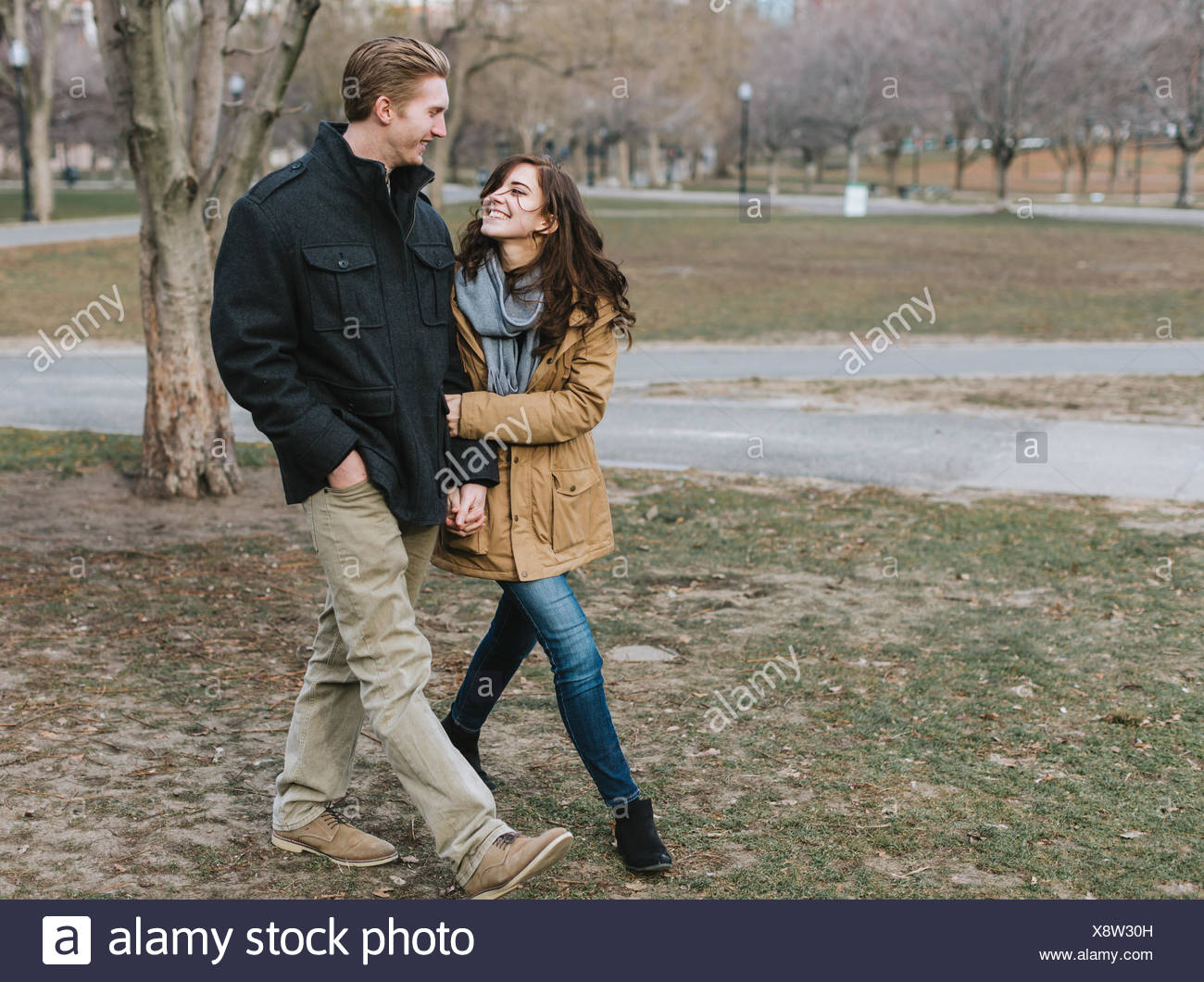 Young Couple Walking Through Park Arm In Arm Smiling Stock Photo Alamy Young Couple Walking Through Park Arm In Arm Smiling Stock Photo Alamy