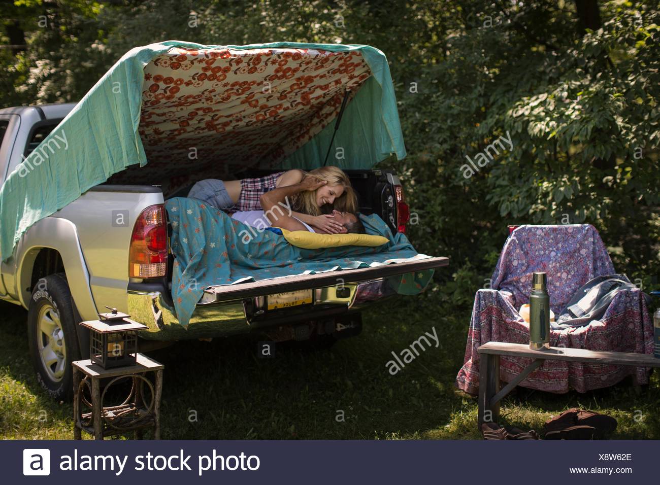 Young Woman Kissing Boyfriend In Pick Up Boot Whilst Camping Stock Photo Alamy