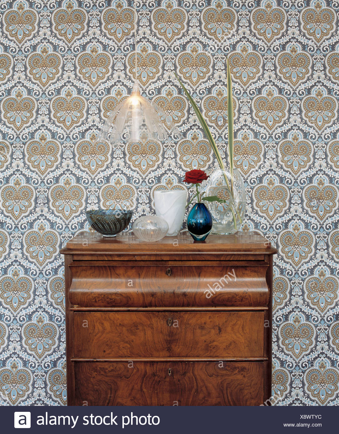 A Chest Of Drawers And An Old Fashioned Wallpaper Stock Photo