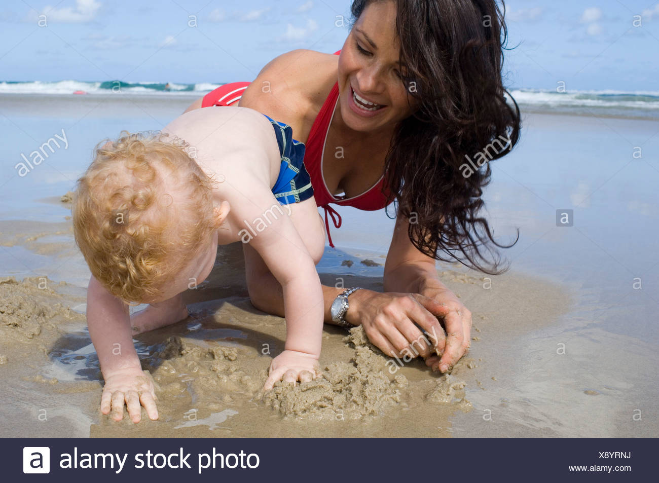 Female Long Brunette Hair Wearing Red Bikini Kneeling On Sandy