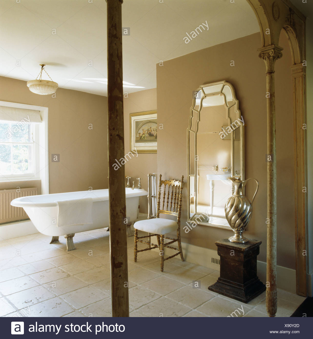 Large Venetian Mirror And Roll Top Bath In Beige Bathroom With