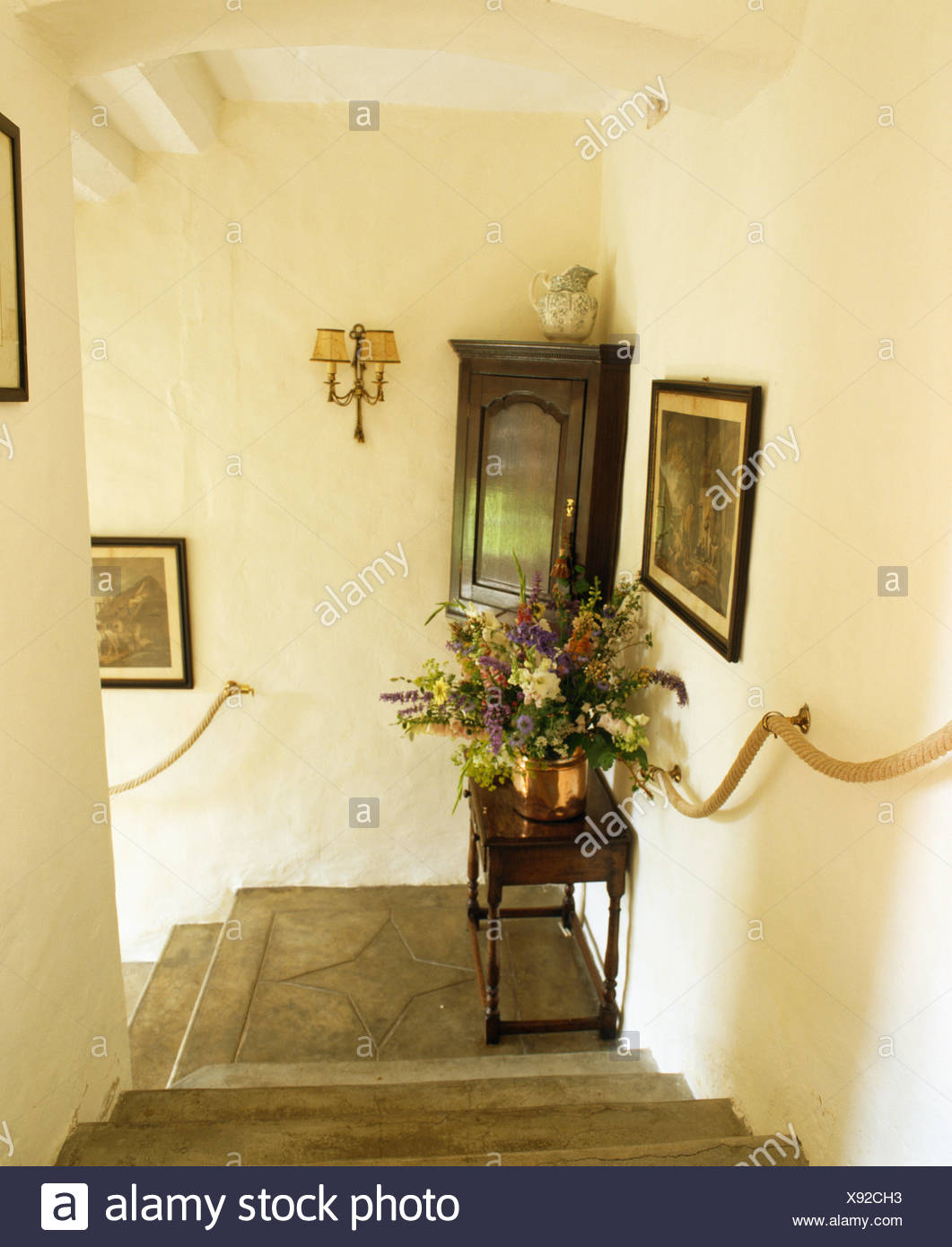 Antique Corner Cupboard And Table At Bend Of Stone Staircase With