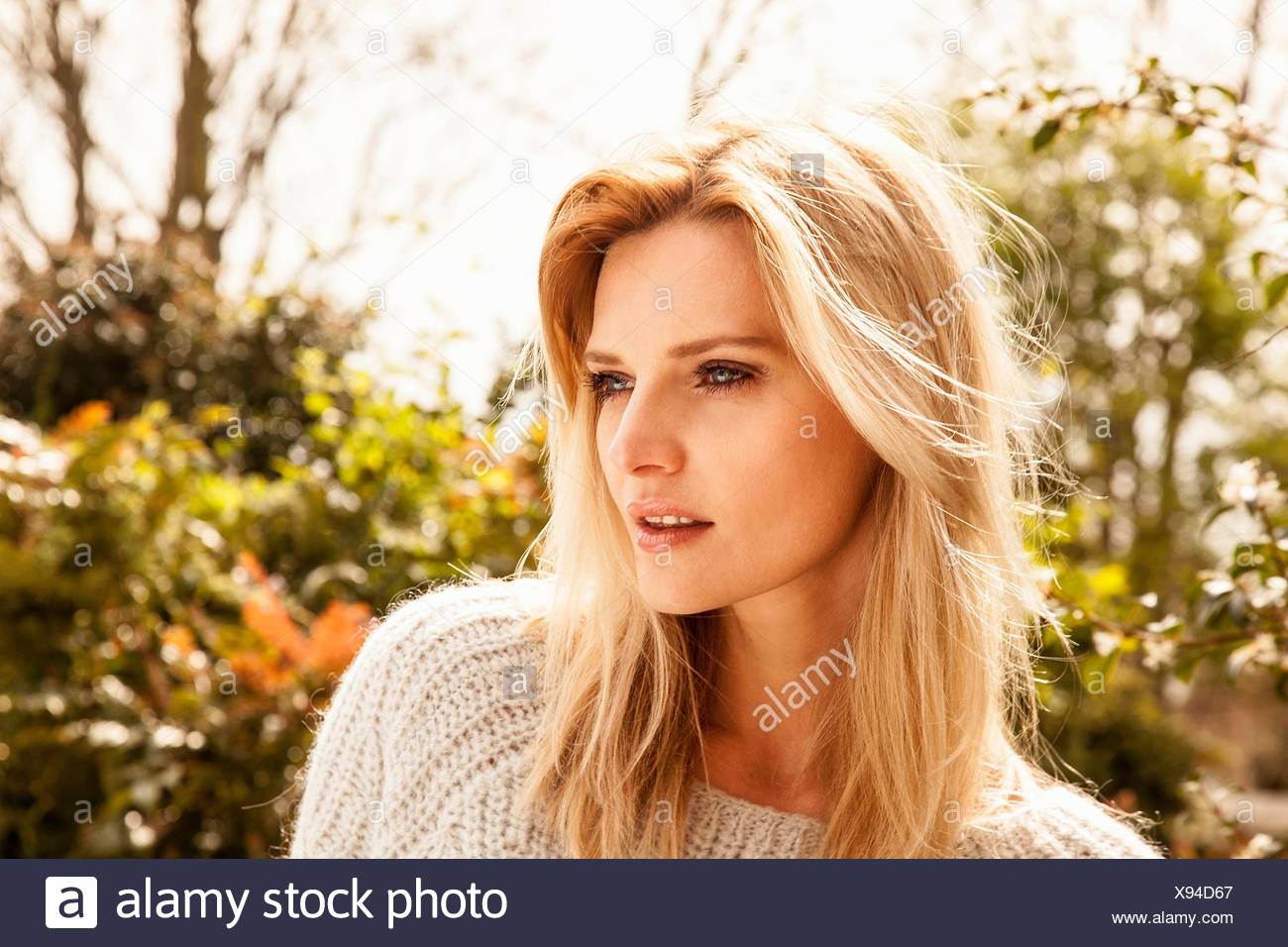 Beautiful mid adult woman with long blond hair in garden Stock Photo