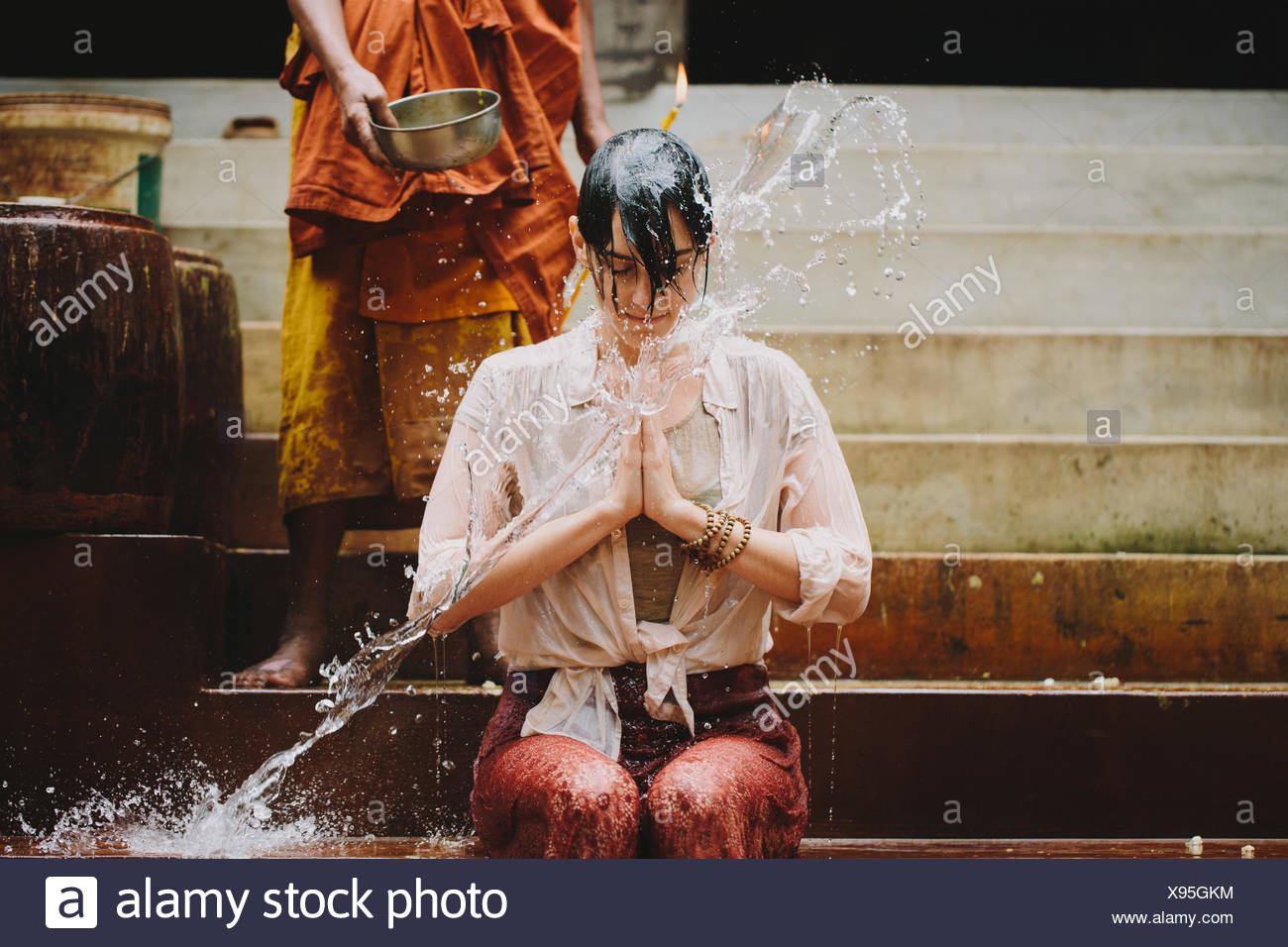 Cambodia, Buddhist monk water blessing young woman Stock Photo