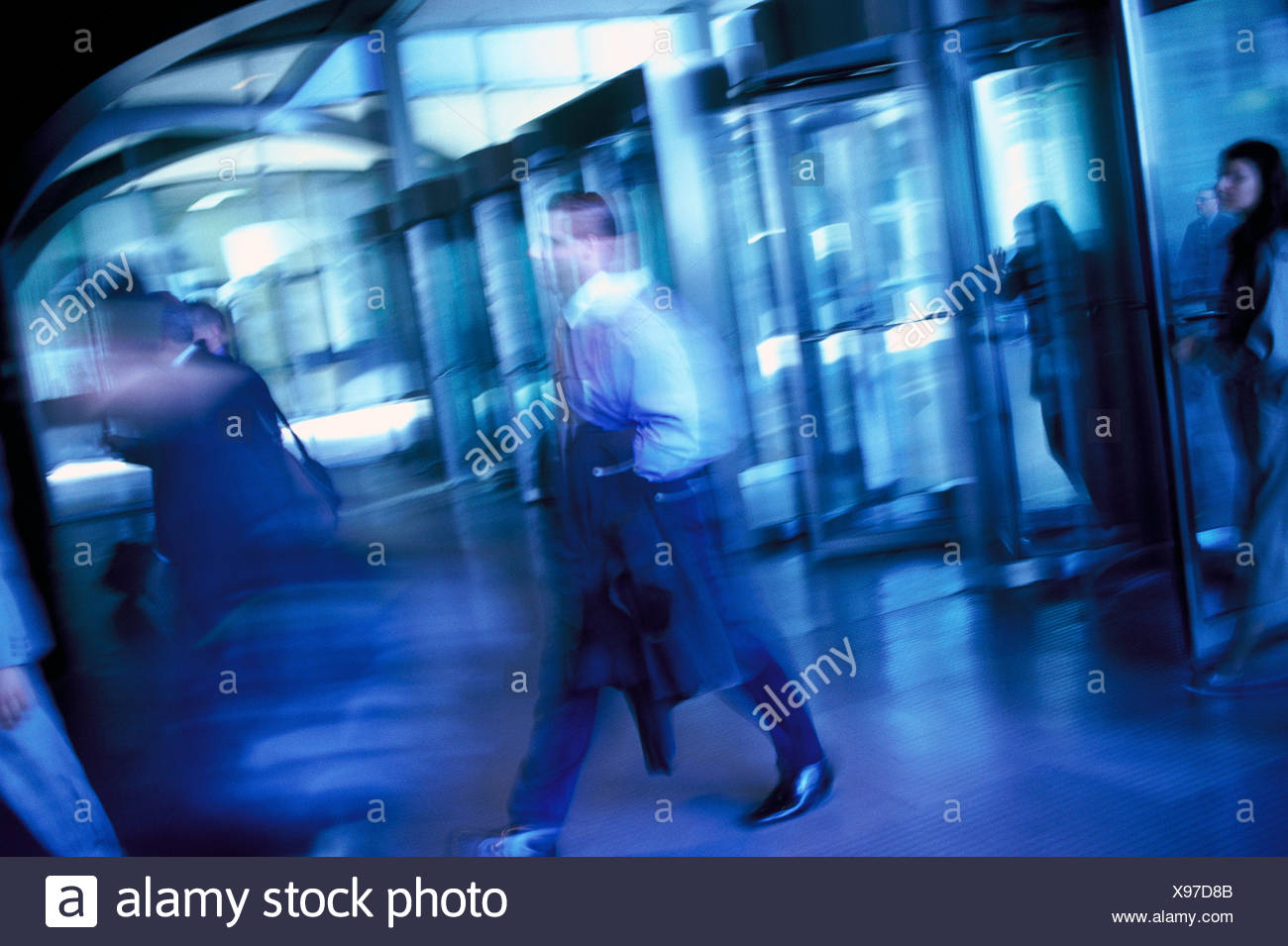 Business People Walking Through Revolving Glass Doors