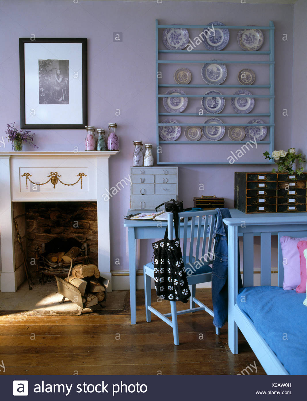 Collection Of Plates On Pale Blue Painted Shelves On Wall Above Painted Table And Chair Beside Living Room Fireplace Stock Photo Alamy
