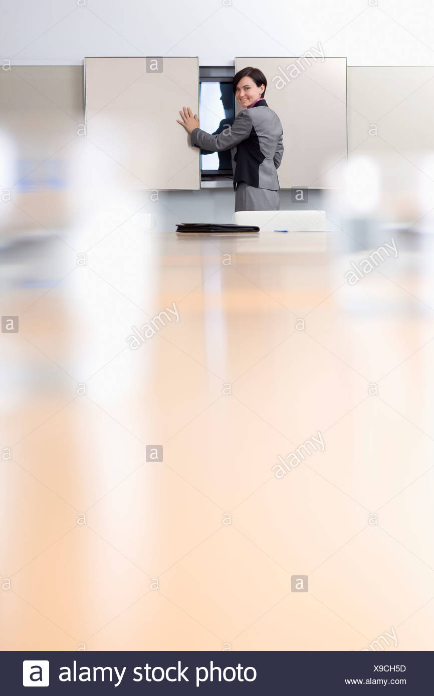 Portrait Of Smiling Businesswoman Opening Cabinet In Conference