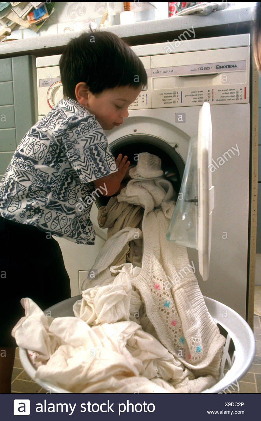 Young Boy Taking Duvet Cover Out Of Washing Machine Stock Photo