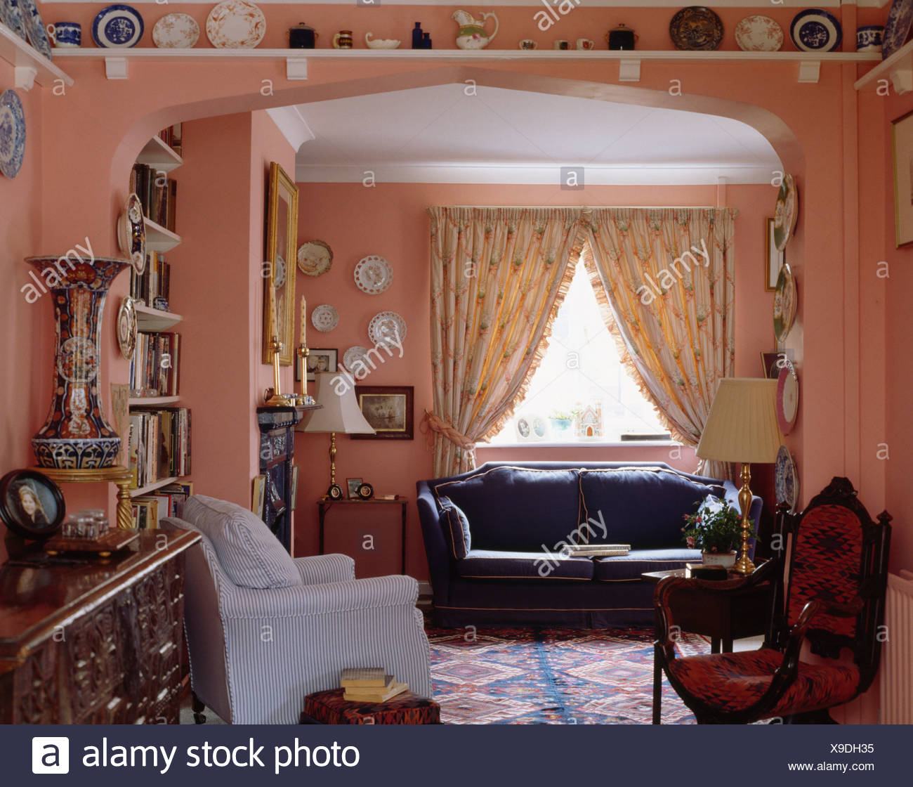 Blue Sofa In Front Of Window With Patterned Cream Curtains In Pink