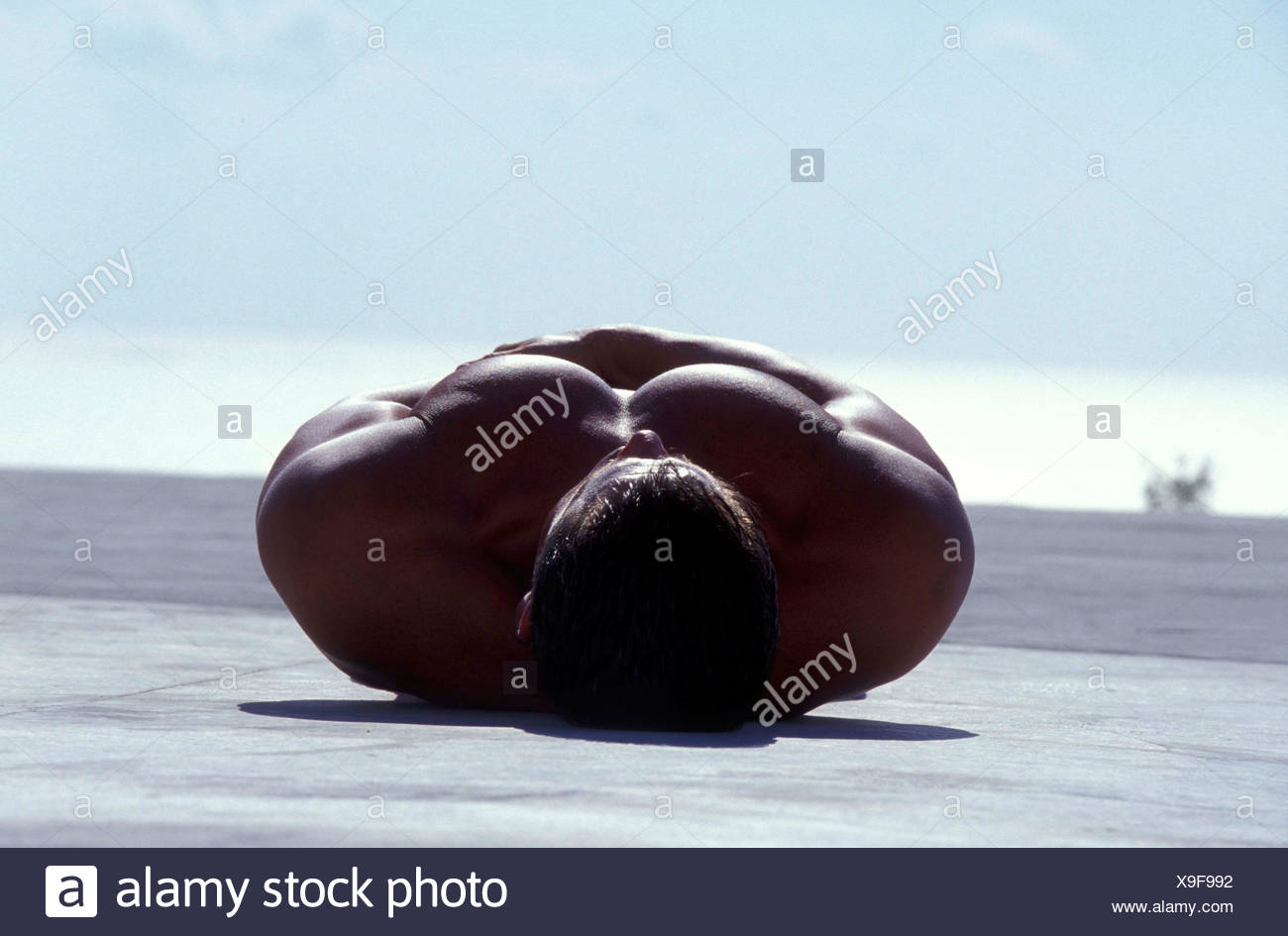 Male With Short Brown Hair Lying On Back Against Horizon Back Of