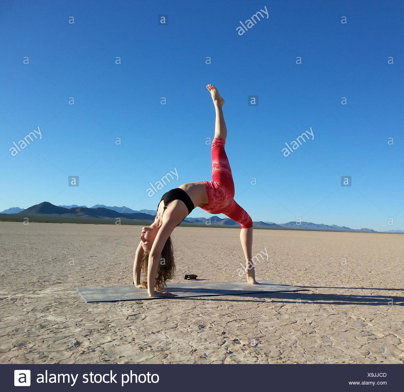 Woman doing a one legged wheel pose in a dry lake, Nevada, United States Stock Photo
