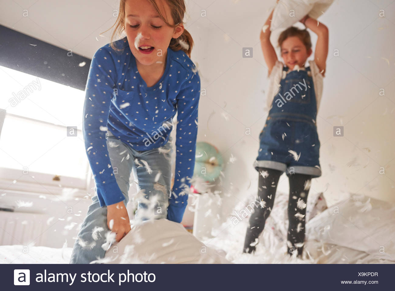 Two Sister Having Feather Pillow Fight On Bed Stock Photo