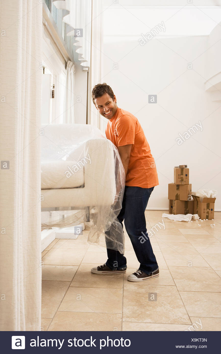 Man Moving House Lifting White Sofa Wrapped In Plastic Sheet