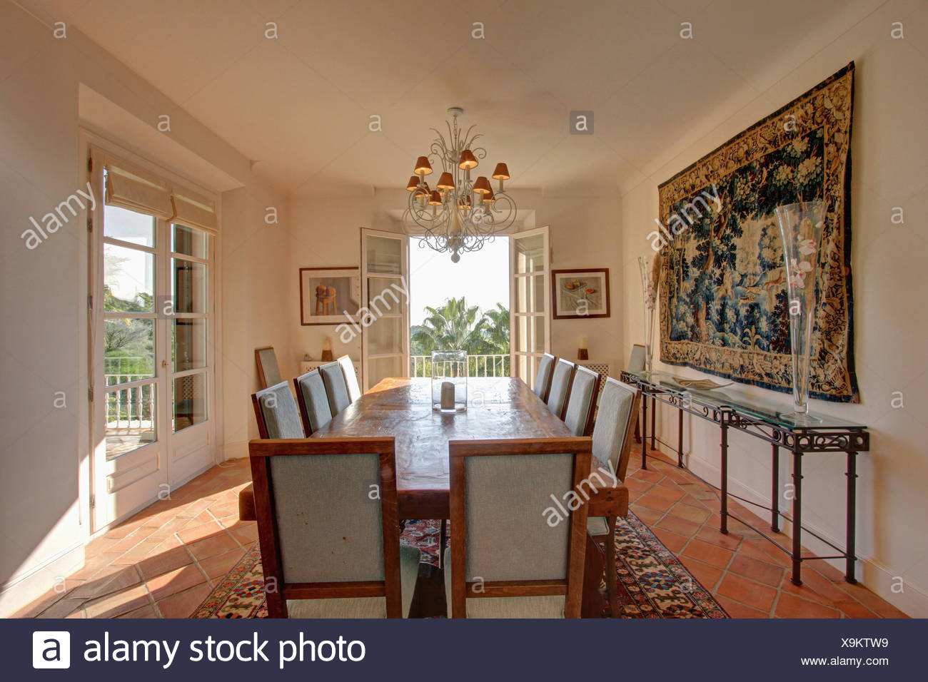 Large Tapestry On Wall Above Glass Metal Console Table In Sunny White Dining Room With Pale Wood Table And Upholstered Chairs Stock Photo Alamy