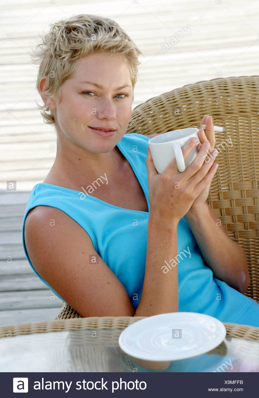 Female Short Blonde Hair Wearing Turquoise Vest Top Sitting