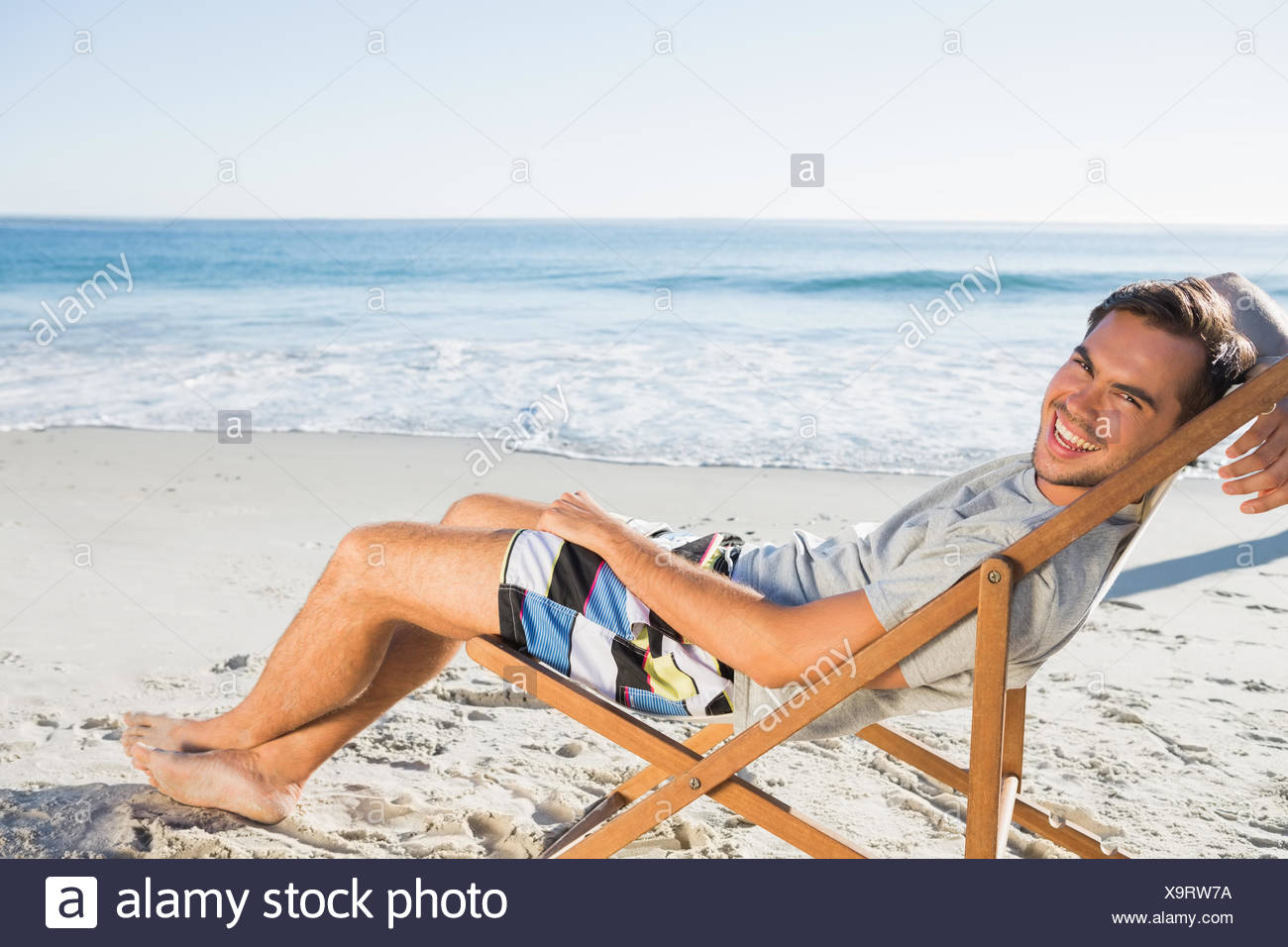 Handsome Man On The Beach Lying On His Deck Chair Smiling At Camera Stock Photo Alamy