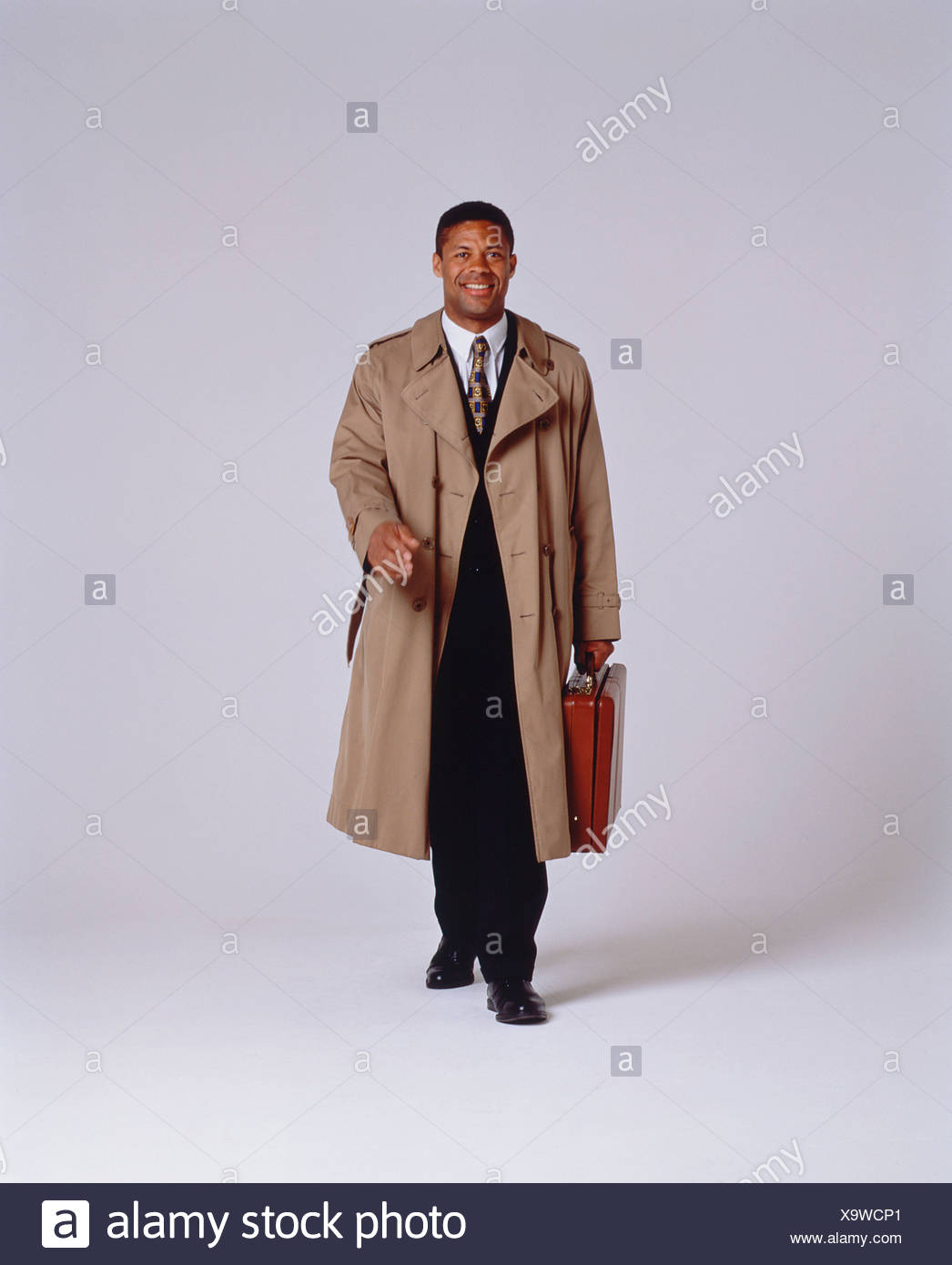 Studio Image Of Young Happy Black Man Wearing Rain Coat Walking