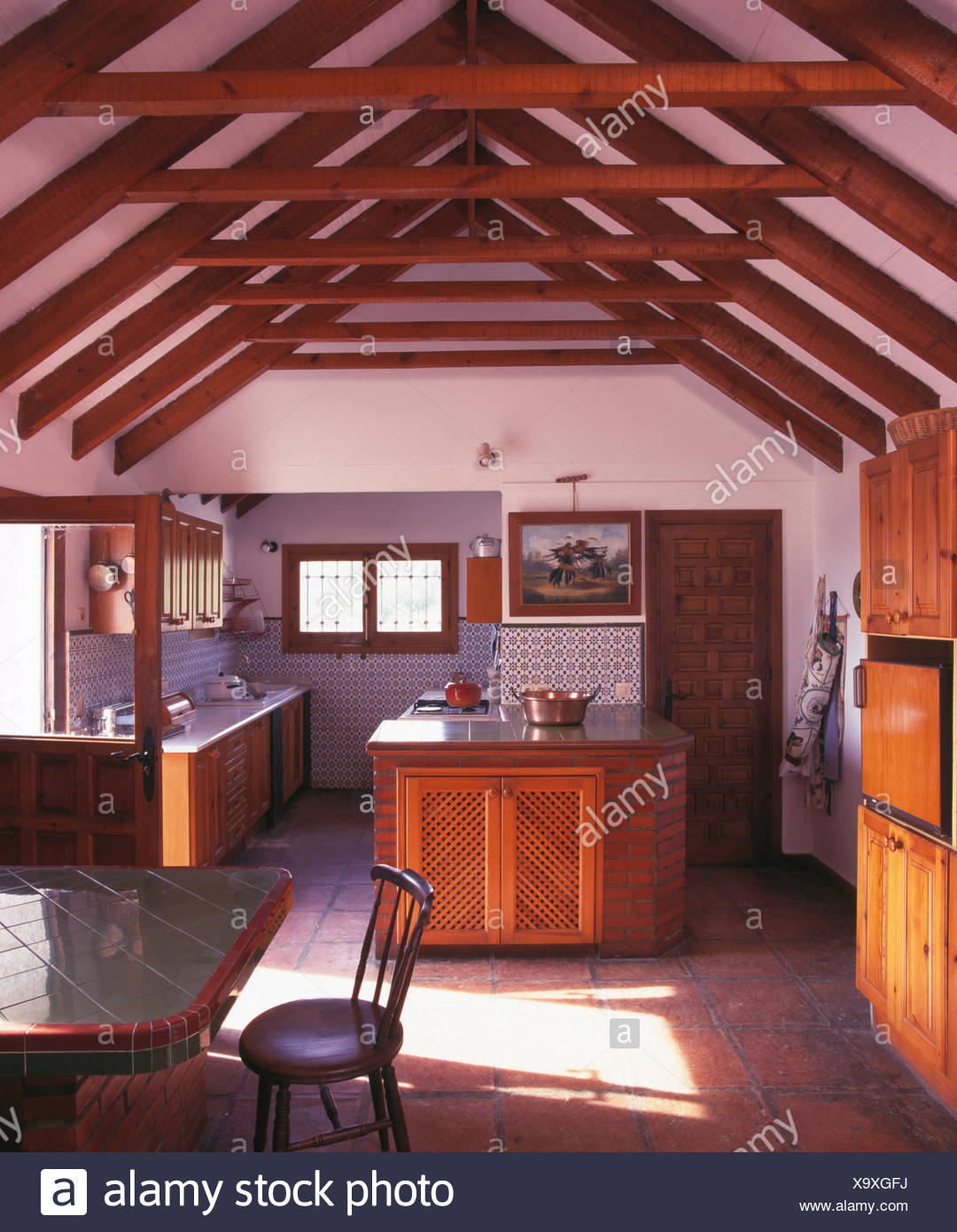 Wooden Beams On Apex Ceiling In Spanish Country Kitchen With