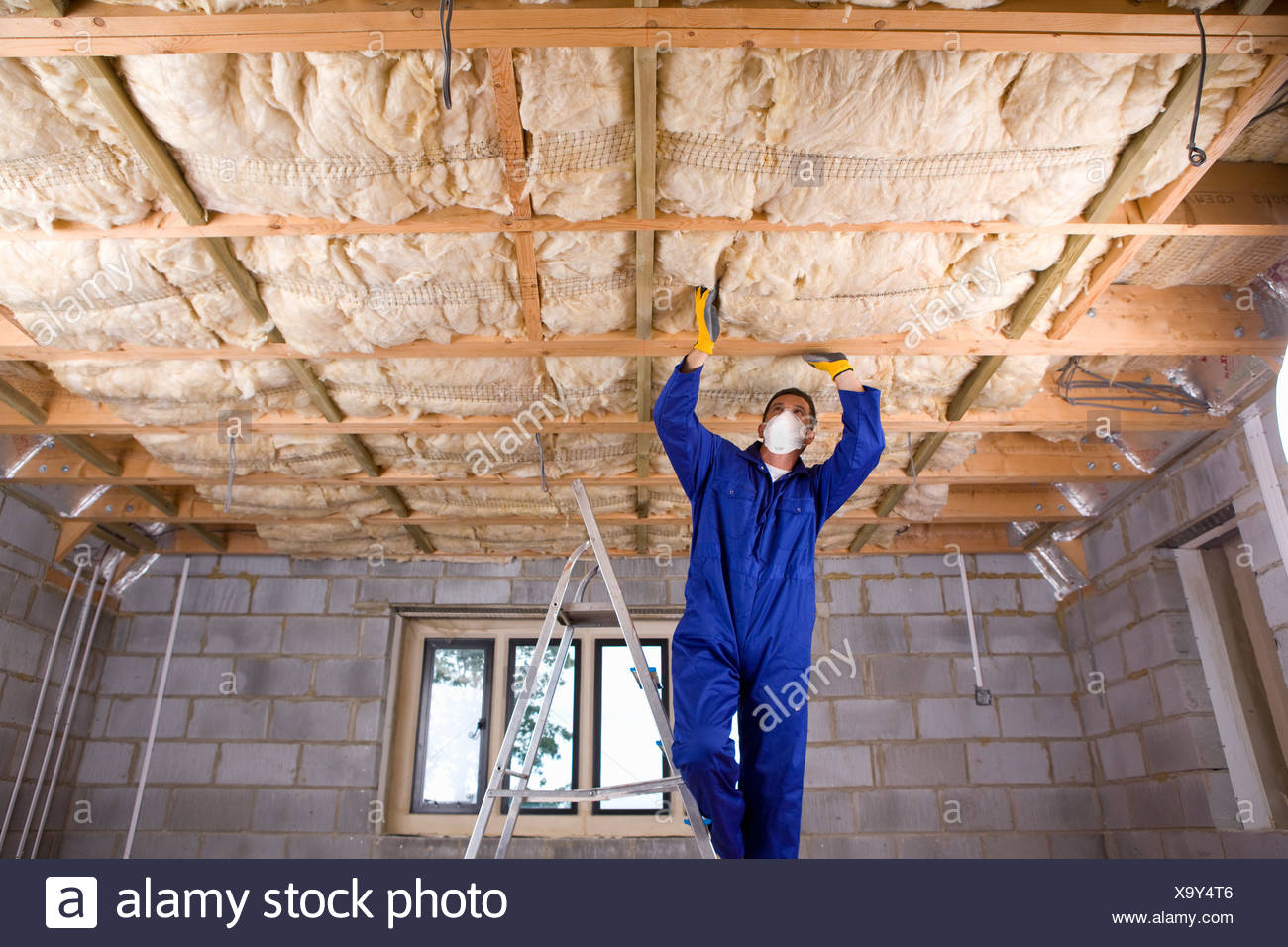 Man In Coveralls And Protective Mask Installing Ceiling