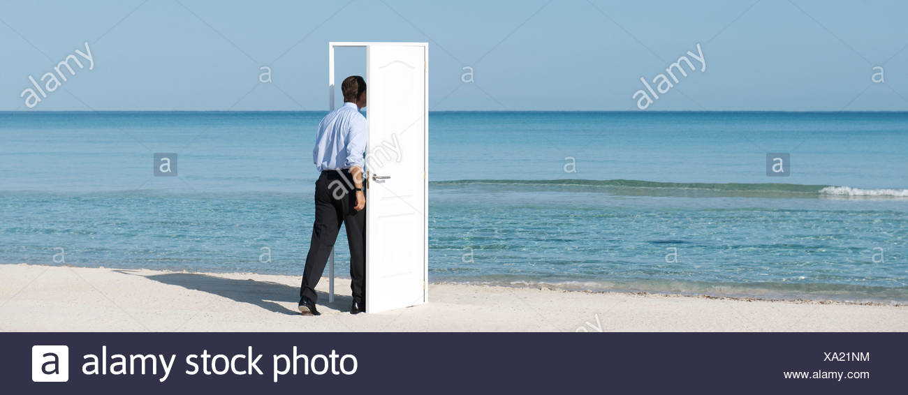 Man Walking Into Open Door On Beach Rear View Stock Photo
